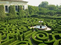 a large garden with a fountain surrounded by hedges