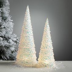 two small white christmas trees sitting next to each other