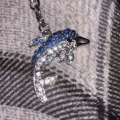 a close up of a necklace on a person's shirt with a dolphin charm