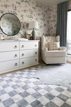 a living room with a dresser, chair and large mirror on it's wall