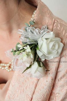 a close up of a woman wearing a pink dress with white flowers on her lapel