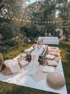 an outdoor dining table set up with white linens and pillows