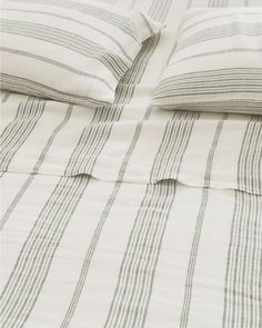 an unmade bed with striped sheets and pillows