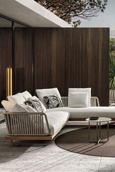 a modern living room with white furniture and wood paneling on the wall behind it