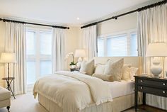 a large bed sitting in the middle of a bedroom next to two lamps on either side of a window