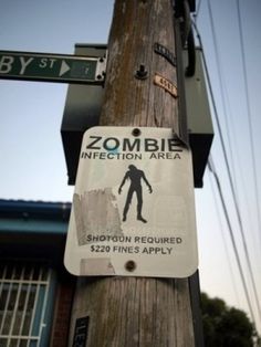 a sign on a telephone pole warns people to be careful about the dangers of zombies