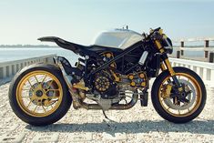 a black and gold motorcycle parked next to the ocean