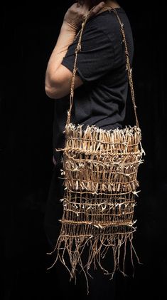 a woman is holding a straw bag made out of sticks and branches, with her hands on her face