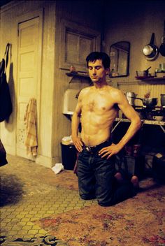 a shirtless man standing in a kitchen with his hands on his hips