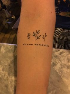 a person with a tattoo on their arm that says, no rain, no flowers