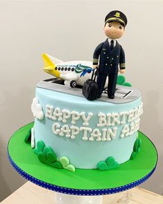 a birthday cake with a toy pilot on top and an airplane in the air behind it