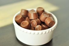 a white bowl filled with chocolate candies on top of a wooden table