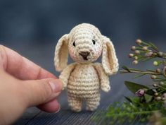 a small crocheted bunny sitting on top of a table next to some flowers