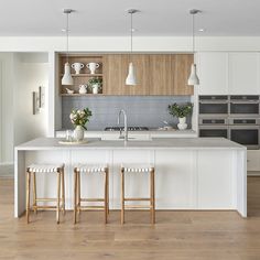 a kitchen with two stools and an island in the middle, surrounded by white cabinets