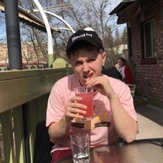 a man sitting at a table with a drink in front of him and his mouth open