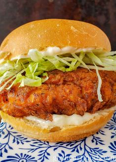 a fried chicken sandwich with lettuce and cheese on a blue and white plate