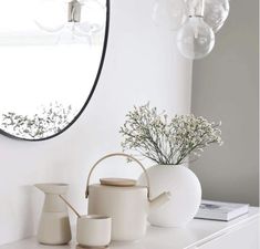 a white table with vases and a mirror on it