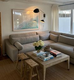 a living room filled with furniture and a painting hanging on the wall above it's windows