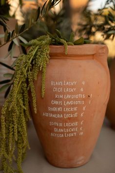 a large clay pot with writing on it and some plants in the backround