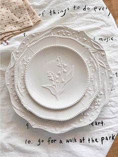 three white plates sitting on top of each other next to napkins and place mats