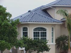 a white house with a blue roof and palm trees