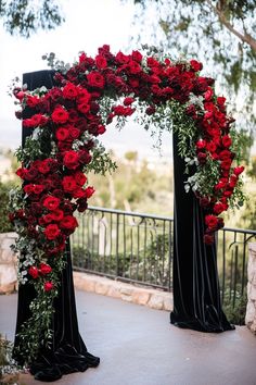 an arch decorated with red roses and greenery