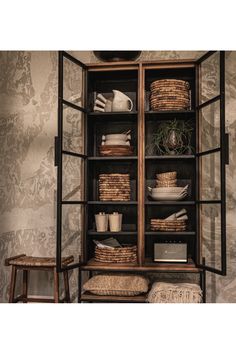 a bookcase with baskets and other items on it in front of a wallpapered background