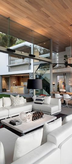 a living room filled with white couches next to a fire place under a wooden ceiling