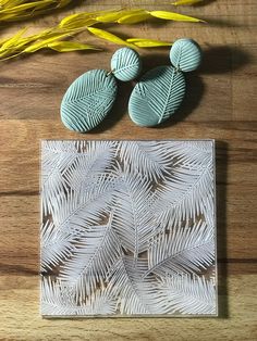 three white and blue leaves are on a wooden surface next to some yellow flowers, one is