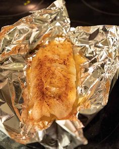 a piece of chicken in foil on top of a stove burner with seasoning