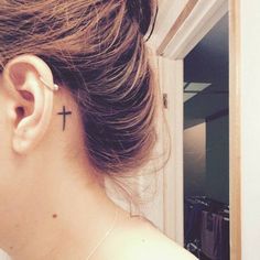 a woman with a cross tattoo behind her ear