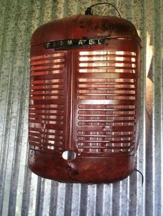 an old red radio sitting on top of a metal sheet covered wall with the word'emaeel'written on it