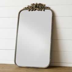 a large mirror sitting on top of a wooden table next to a white brick wall