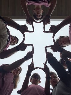 a group of people standing in a circle with their hands together to form the shape of a heart