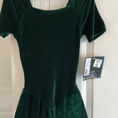 a green dress hanging on a door with a tag attached to the back of it