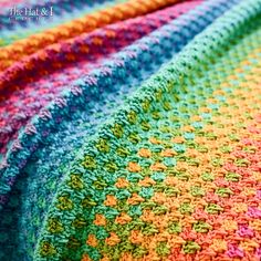 a multicolored crocheted blanket on top of a bed