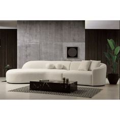 a living room with a large white couch and coffee table in front of a gray wall