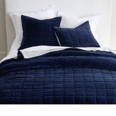 a bed with blue comforter and pillows on it