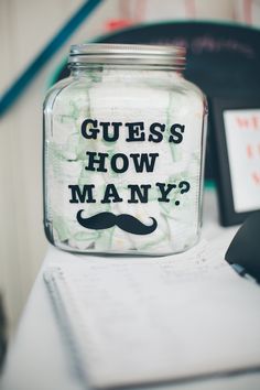 a glass jar with the words guess how many? on it sitting on a desk