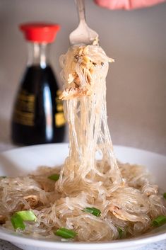 someone is lifting noodles from a white bowl