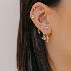 a close up of a woman's ear wearing gold earrings