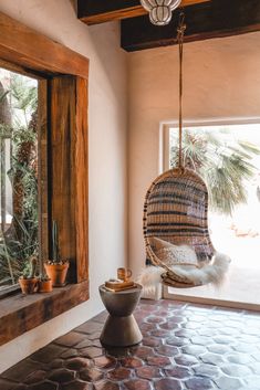 a hammock hanging from the ceiling next to a window with potted plants