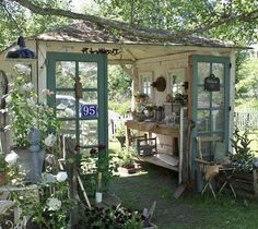 a small shed with lots of potted plants on the front and back porch area