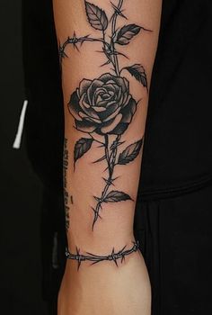 a rose tattoo on the arm with barbed wire