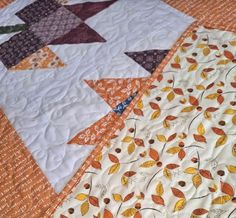 an orange and white quilted table topper with autumn leaves on it's edges