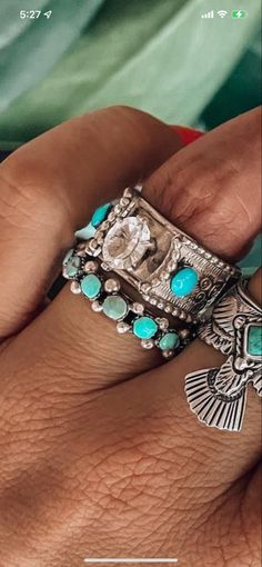 a woman's hand holding a ring with turquoise stones and an angel on it