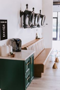 a kitchen with green cabinets and white counter tops next to a wall mounted coffee maker