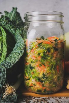 a jar filled with vegetables sitting on top of a wooden cutting board