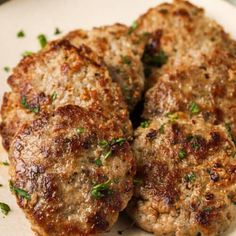 some meat patties on a white plate with parsley sprinkled on top