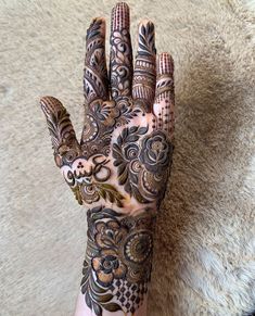 a person's hand with hennap and tattoos on it, resting against a carpet